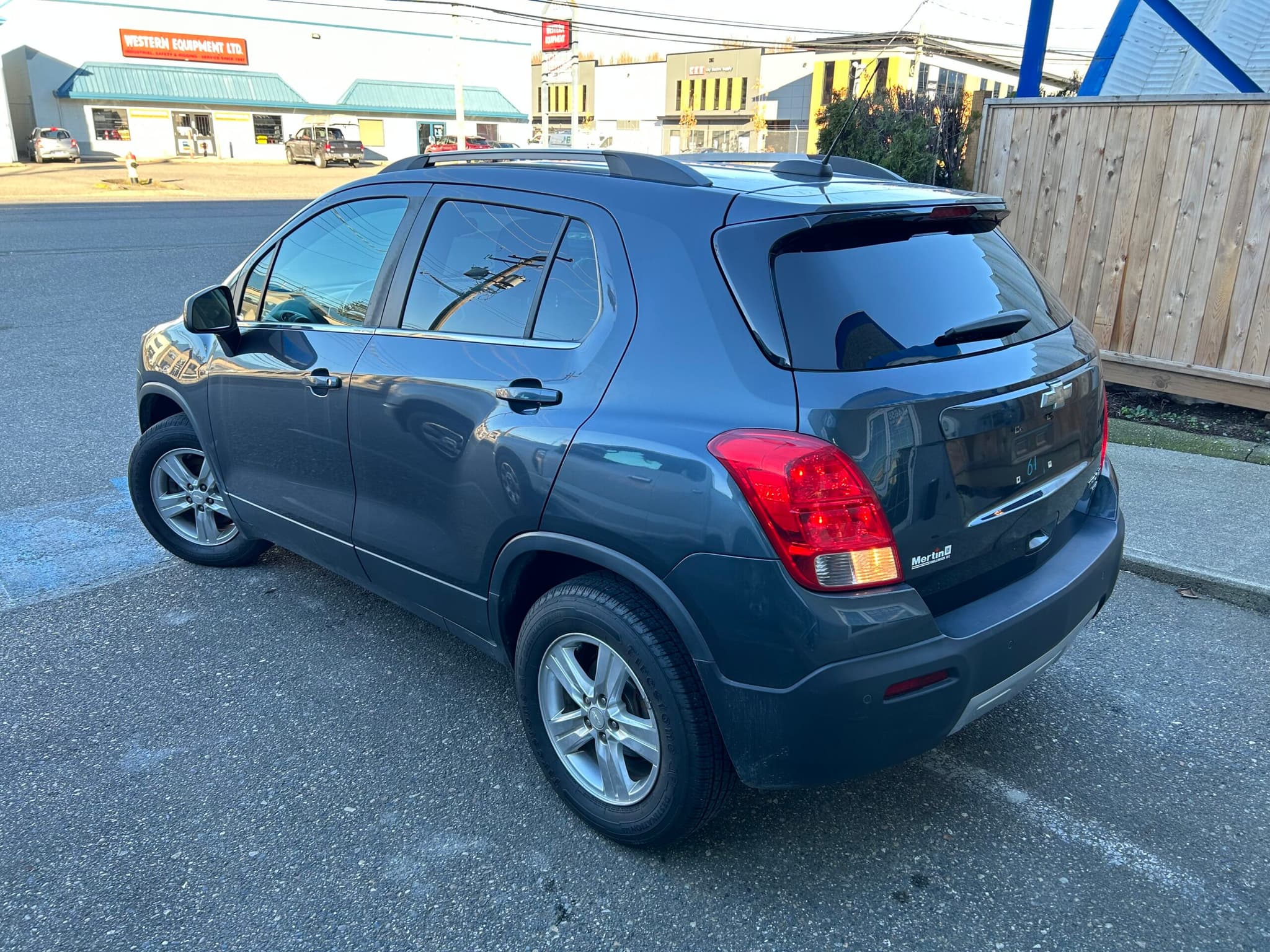 The same grey Trax from the rear driver's side, showing the tailgate, roof rails and alloy wheels