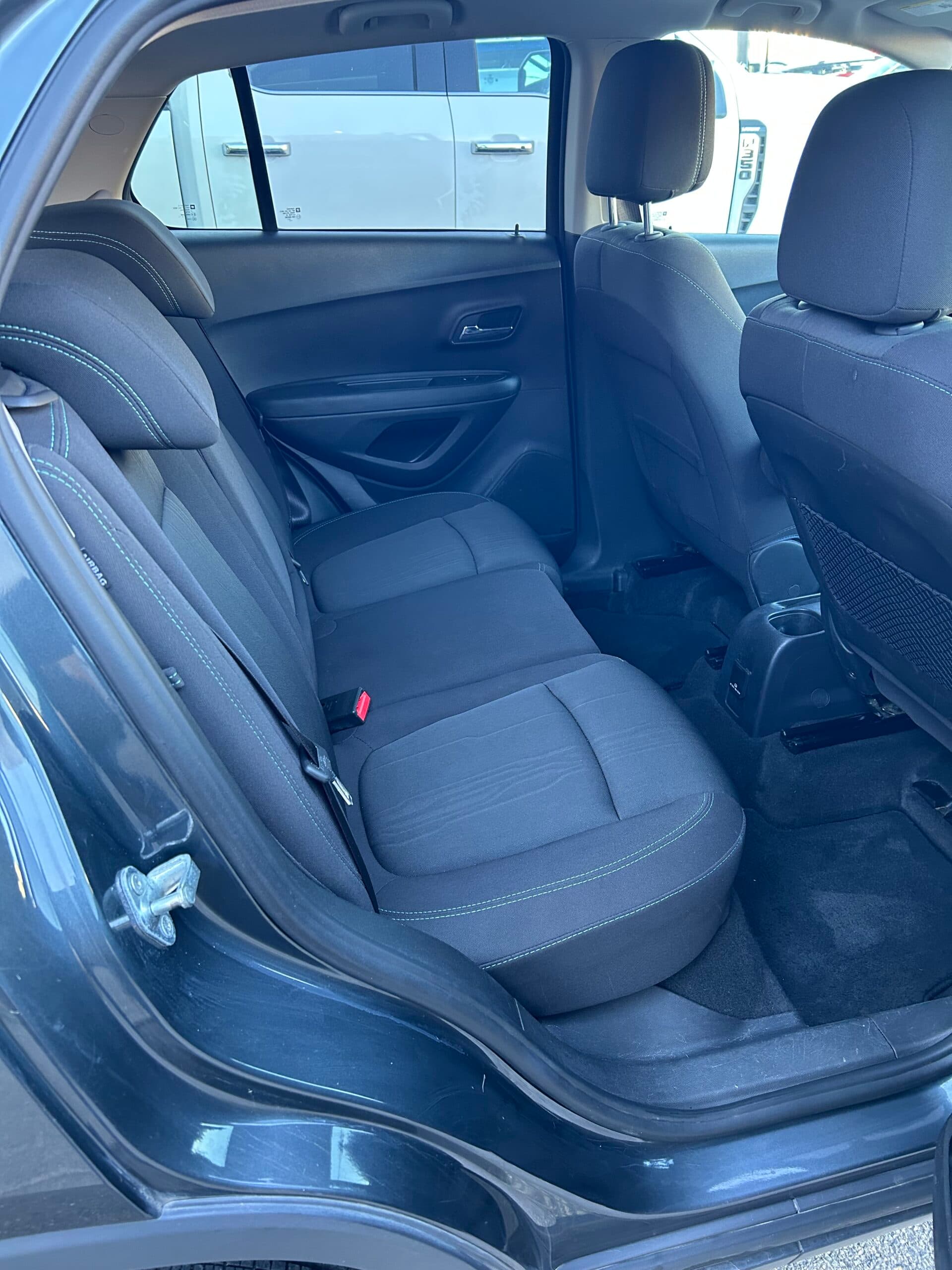 Rear bench seat of the Trax in black cloth, seen through the open rear passenger door