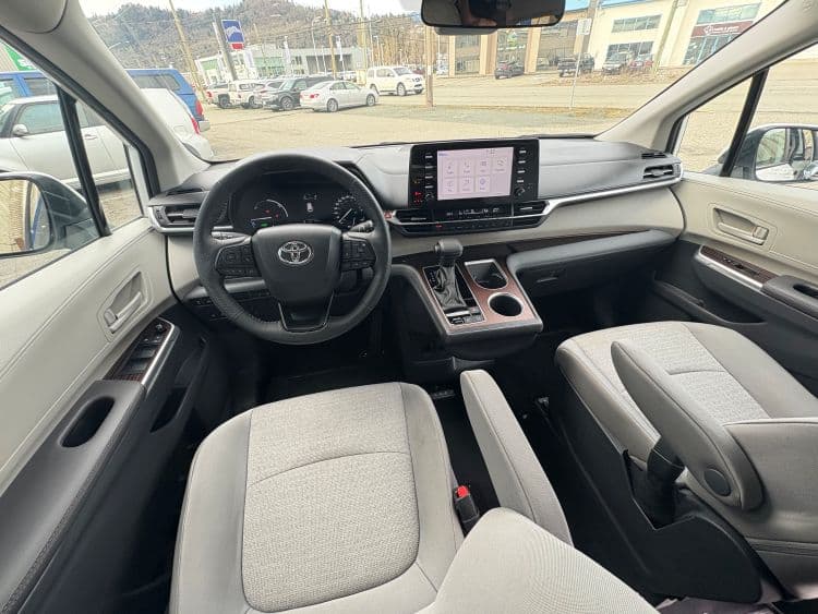 Driver's area of the Sienna: leather-wrapped steering wheel, hybrid instrument cluster and a nine-inch touchscreen, with grey cloth front seats