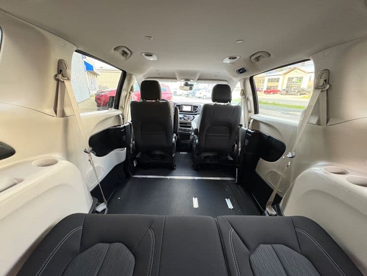 Interior from the rear hatch looking forward down the lowered floor, with the second row seats flipped up against the walls to leave a clear path between the front seats