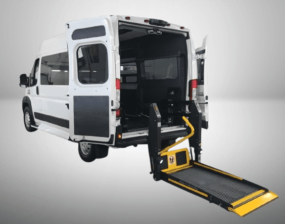 A full-size high-roof van with a platform lift lowered to the ground at the rear doors